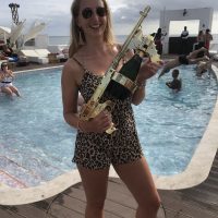 A woman by the pool holding a water gun